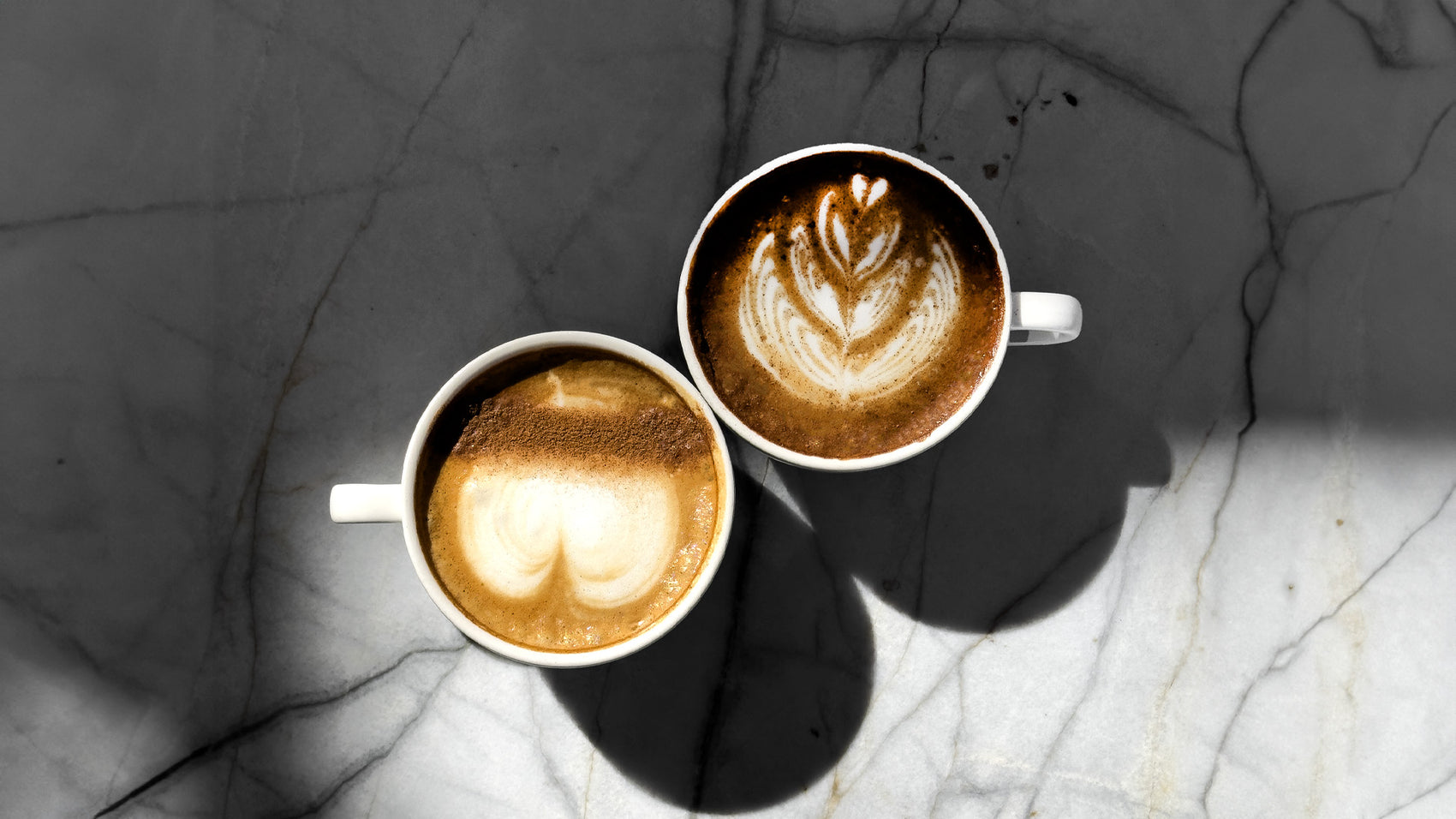 The image shows several cups of freshly brewed coffee, elegantly presented with smooth, velvety surfaces showcasing beautiful latte art. The warm, inviting colors of the coffee contrast with the simple, stylish cups. The overall scene evokes a sense of comfort and indulgence, emphasizing the high-quality coffee and the relaxing experience that C Market Coffee offers.
