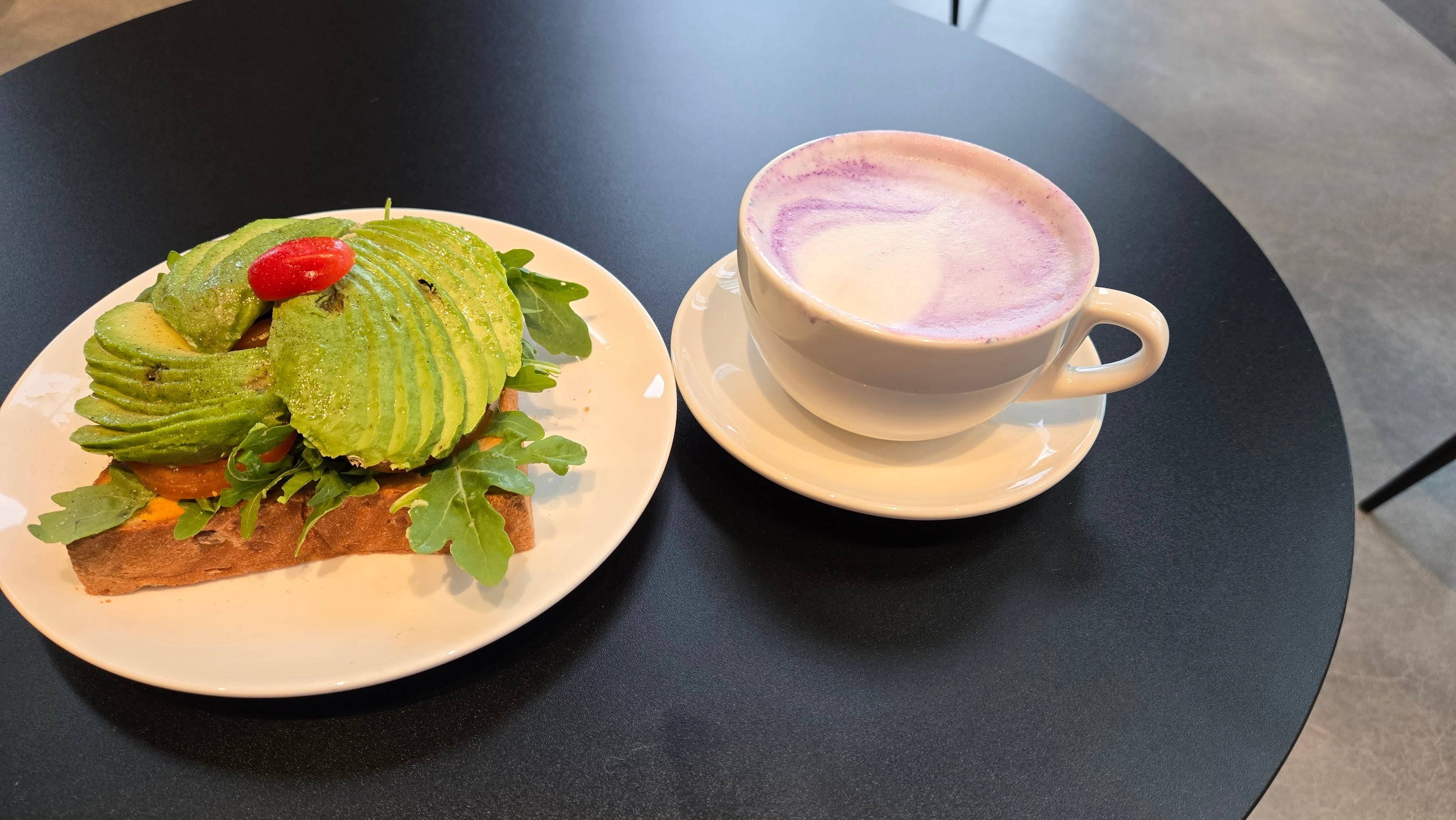 A cozy space at C Market Coffee where a customer enjoys an Ube Latte and Avocado Toast while working on their resume, showcasing the vibrant and inviting atmosphere of the café.