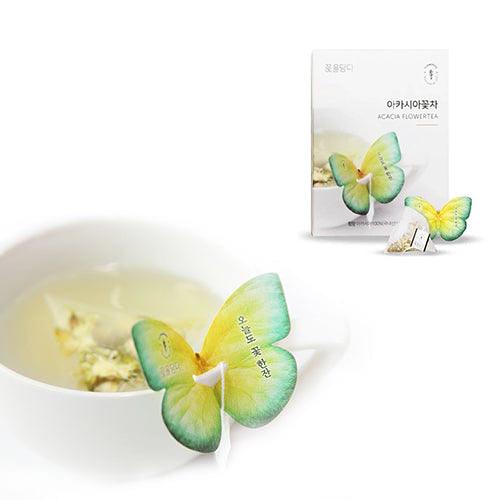 A close-up side view of a tea cup with a butterfly-shaped tea bag, displaying the delicate details of the cup's design and the fluttering wings of the tea bag.