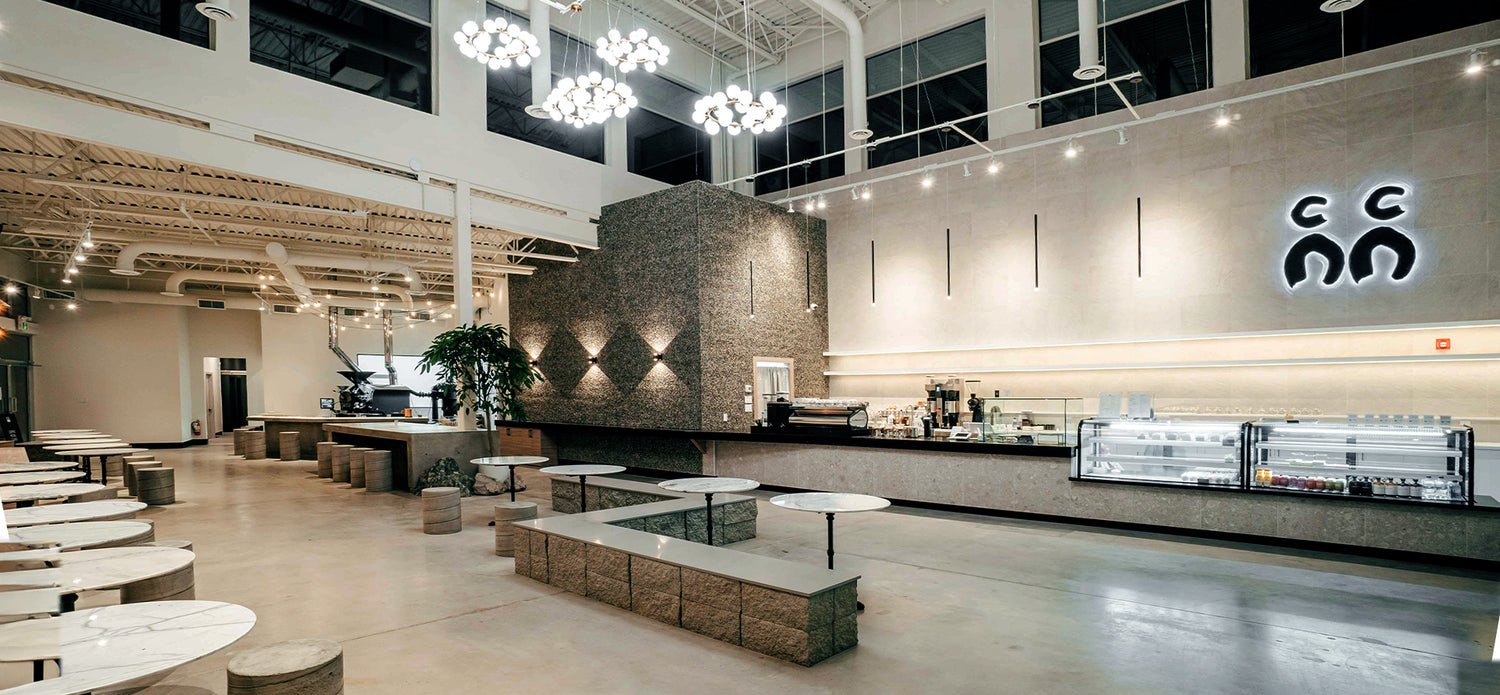 Stylish and inviting café interior located in Port Coquitlam, showcasing a spacious and modern design with tall ceilings that create an airy, open atmosphere. The bright, well-lit space is designed to provide a comfortable and relaxing environment for customers to enjoy their coffee and meals in a welcoming and contemporary setting.