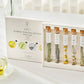 A beautifully arranged Assorted Flower Tea Sticks Gift Set, containing five handcrafted tea sticks in the shape of flowers, each with its own stem. The tea sticks are carefully packaged in a clear glass test tube and a decorative gift box. The set includes two Mugwort Tea Sticks, one Chrysanthemum Tea Stick, one Korean Mint Tea Stick, and one Siberian Chrysanthemum Tea Stick, offering a unique and luxurious tea experience.