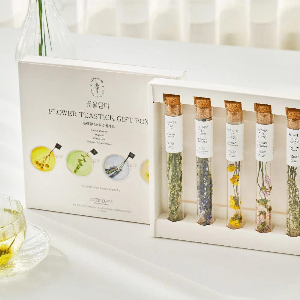 A beautifully arranged Assorted Flower Tea Sticks Gift Set, containing five handcrafted tea sticks in the shape of flowers, each with its own stem. The tea sticks are carefully packaged in a clear glass test tube and a decorative gift box. The set includes two Mugwort Tea Sticks, one Chrysanthemum Tea Stick, one Korean Mint Tea Stick, and one Siberian Chrysanthemum Tea Stick, offering a unique and luxurious tea experience.