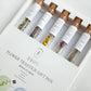 A close-up view of the Assorted Flower Tea Sticks Gift Set, showcasing the five delicate handmade tea sticks in floral shapes. The tea sticks are elegantly arranged inside a glass test tube, placed within a decorative gift box, highlighting the unique presentation. The set features Mugwort, Chrysanthemum, Korean Mint, and Siberian Chrysanthemum tea sticks, offering an aesthetic and functional tea experience.