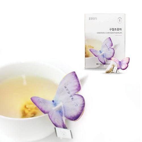 A butterfly-shaped tea bag held by the edge of a glass containing Siberian Chrysanthemum tea. The vibrant colors of the tea and delicate design of the butterfly holder create a calming and elegant presentation.