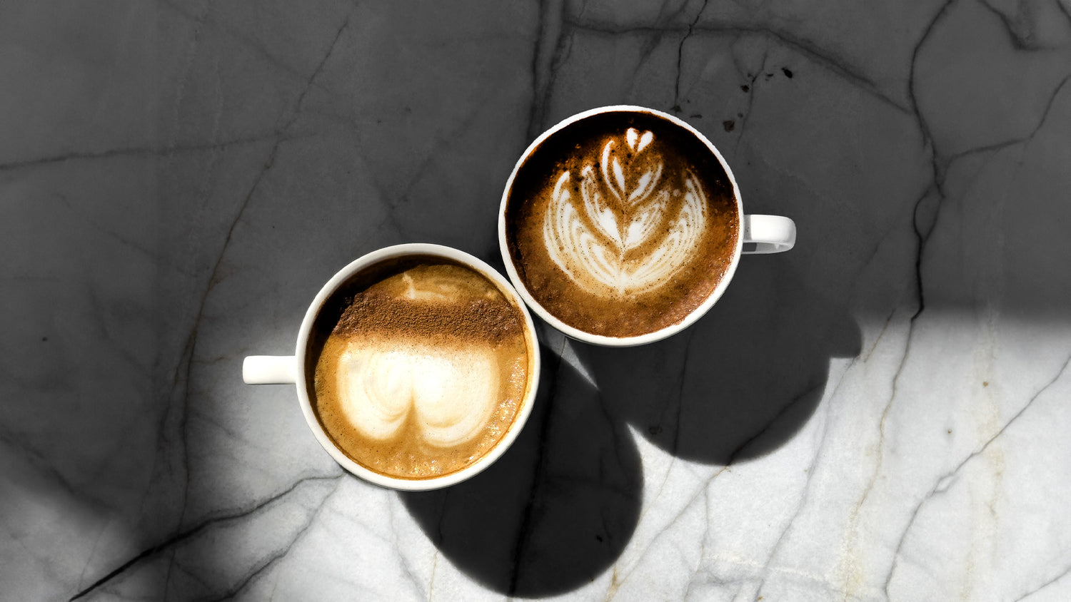 The image shows several cups of freshly brewed coffee, elegantly presented with smooth, velvety surfaces showcasing beautiful latte art. The warm, inviting colors of the coffee contrast with the simple, stylish cups. The overall scene evokes a sense of comfort and indulgence, emphasizing the high-quality coffee and the relaxing experience that C Market Coffee offers.