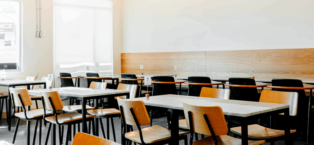 A cozy café interior with warm, ambient lighting illuminating neatly arranged tables and comfortable seating. The design features wooden accents and modern décor, creating an inviting and stylish atmosphere for patrons at C Market Coffee's Coquitlam location.