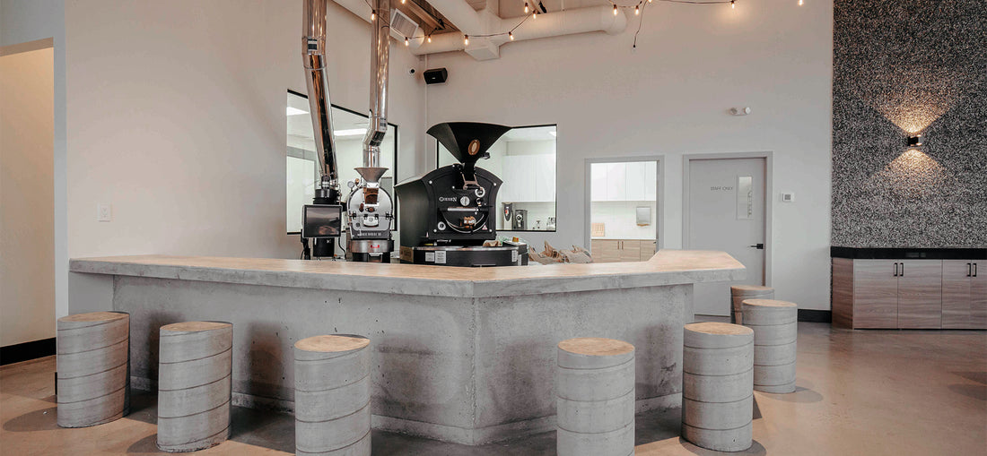 Elegant seating arrangement at C Market Coffee, featuring stylish chairs and tables arranged around a sleek coffee bar, with a high-end brew machine prominently displayed, highlighting the café's dedication to quality and craftsmanship in every cup.